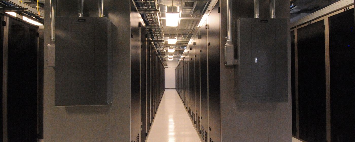 A row of secured server cabinets down the aisle of a data centre