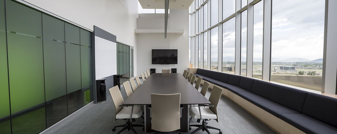 An empty glass-walled boardroom with a long table, ready for a governance meeting