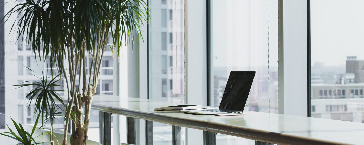 A laptop on a bench by an office window