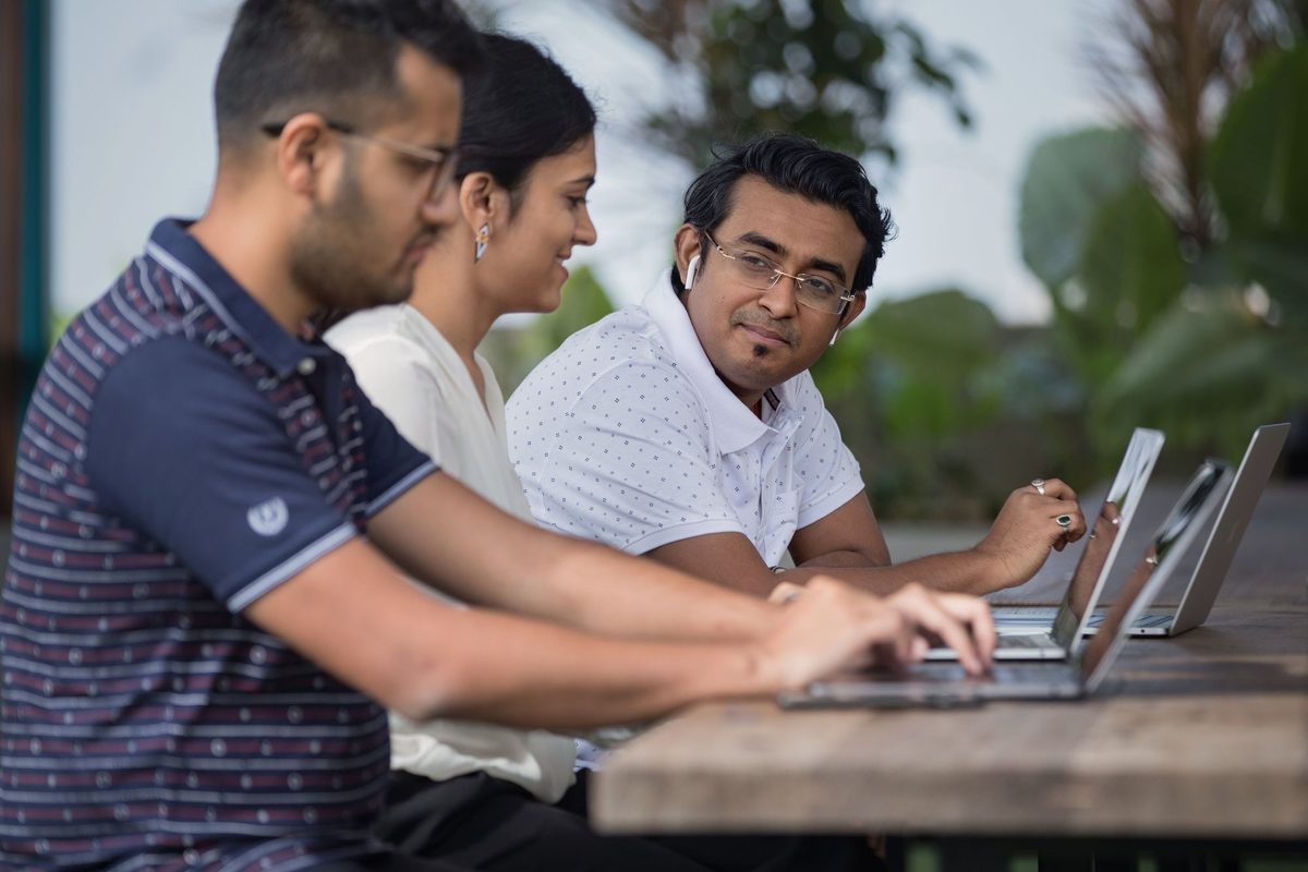 Three colleagues working side by side on laptops