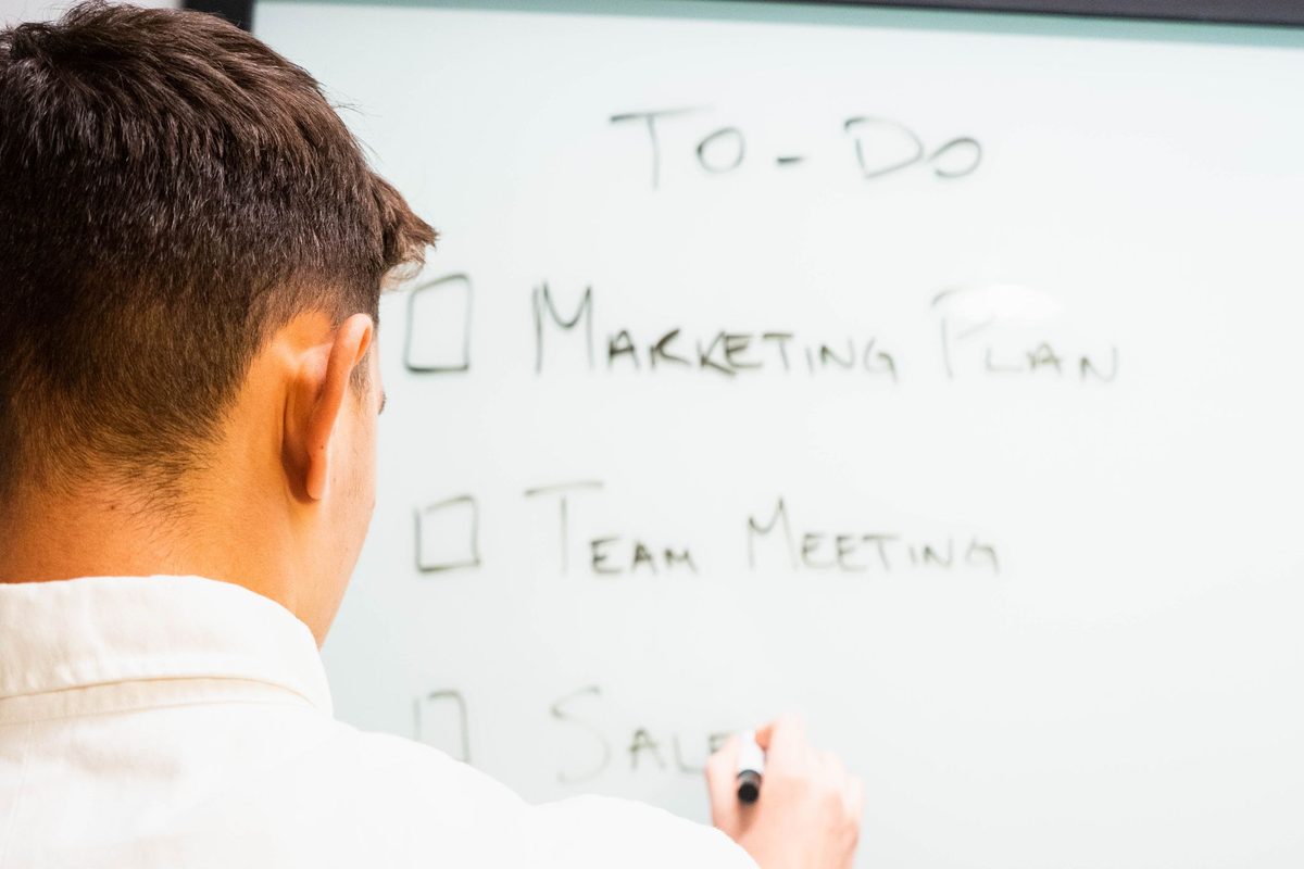 A man writing a to-do list on a whiteboard