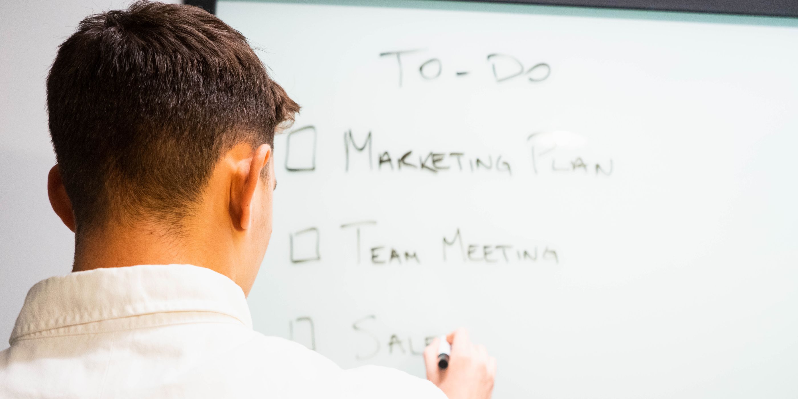 A man writing a to-do list on a whiteboard