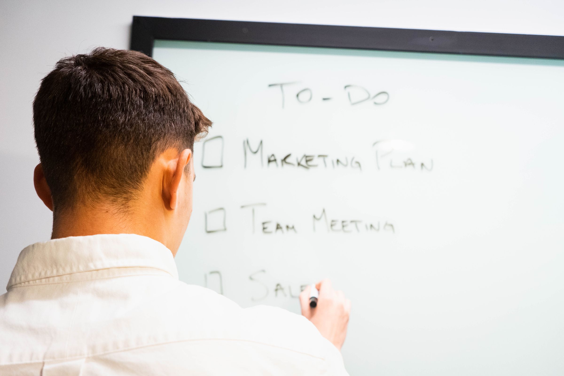 A man writing a to-do list on a whiteboard