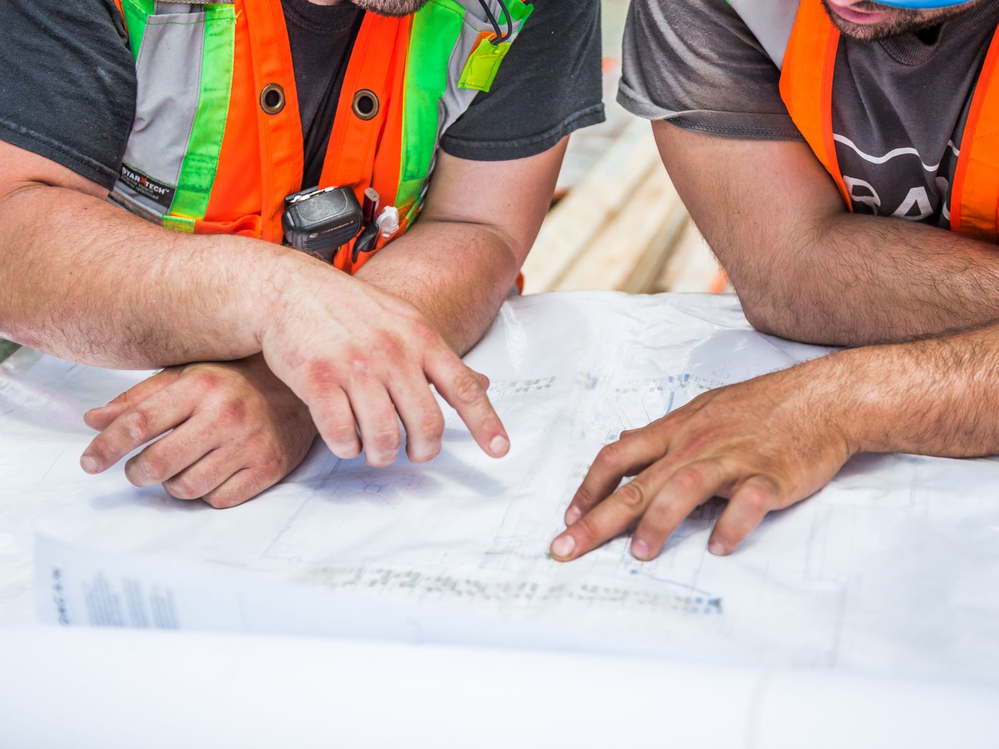 Engineers in hi-vis vests pointing at plans on a table