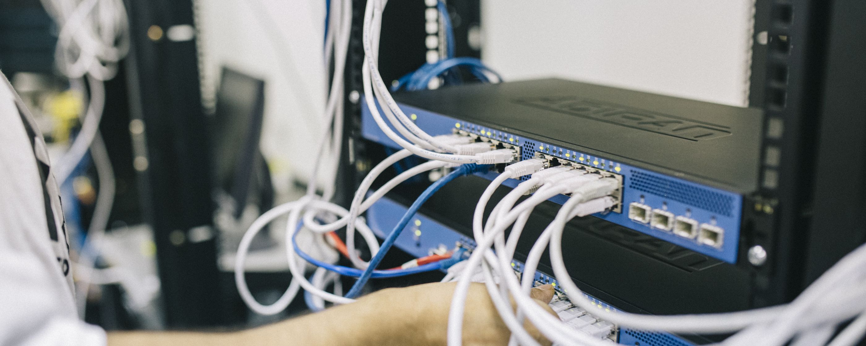 A technician plugging cables into a network switch