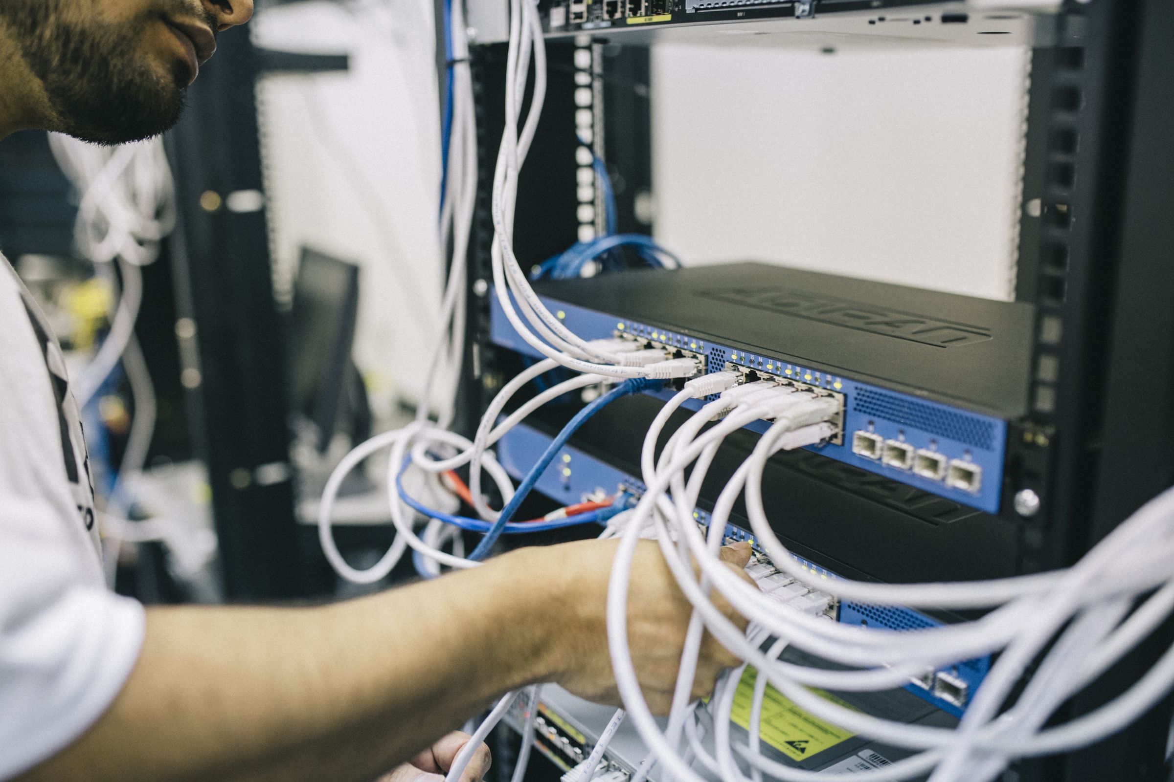 A technician plugging cables into a network switch
