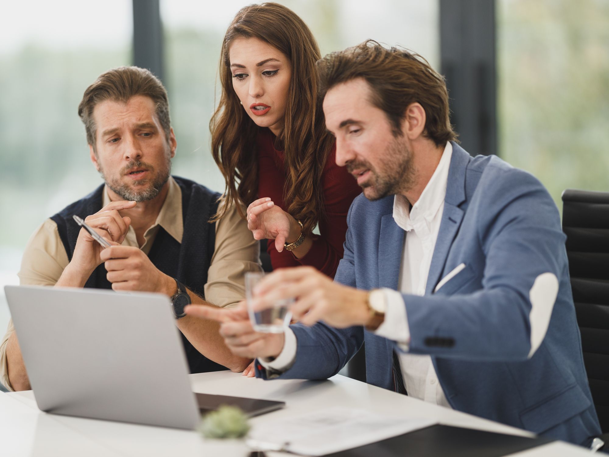 Three colleagues pointing at a laptop screen together