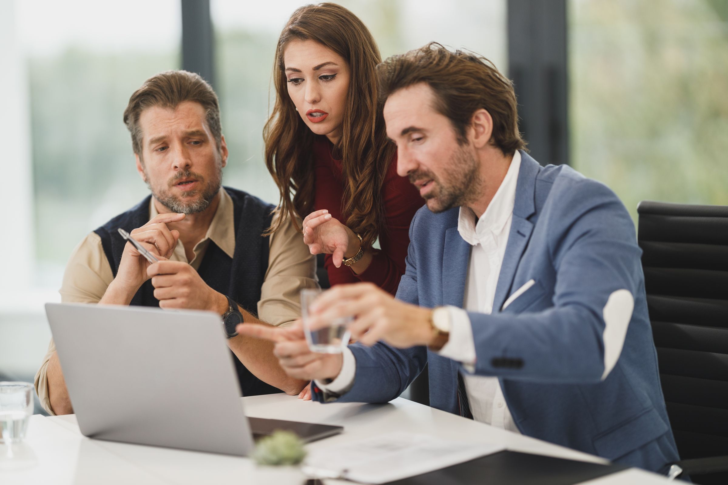 Three colleagues pointing at a laptop screen together