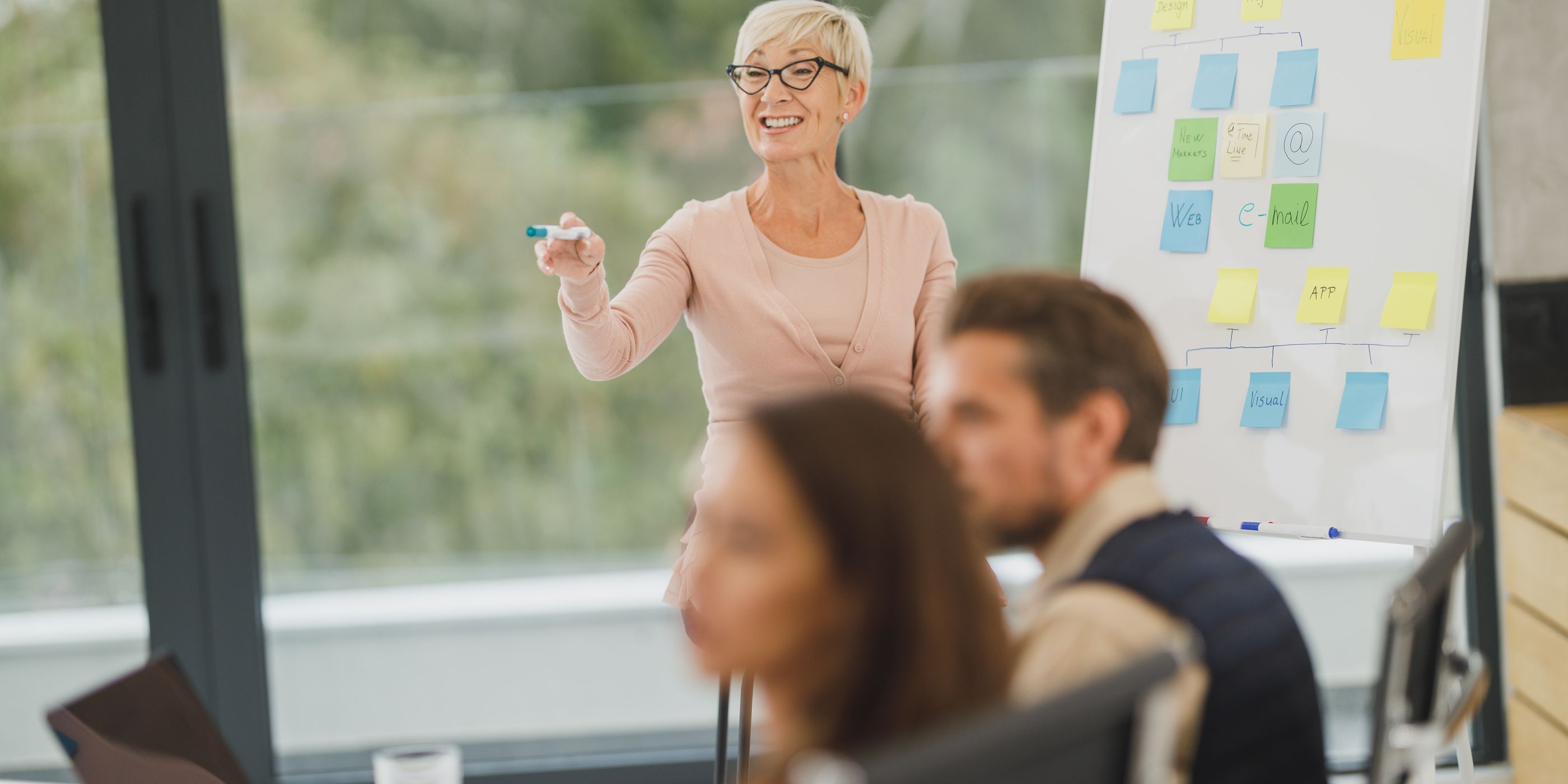 A woman presenting a sticky-note plan to her team