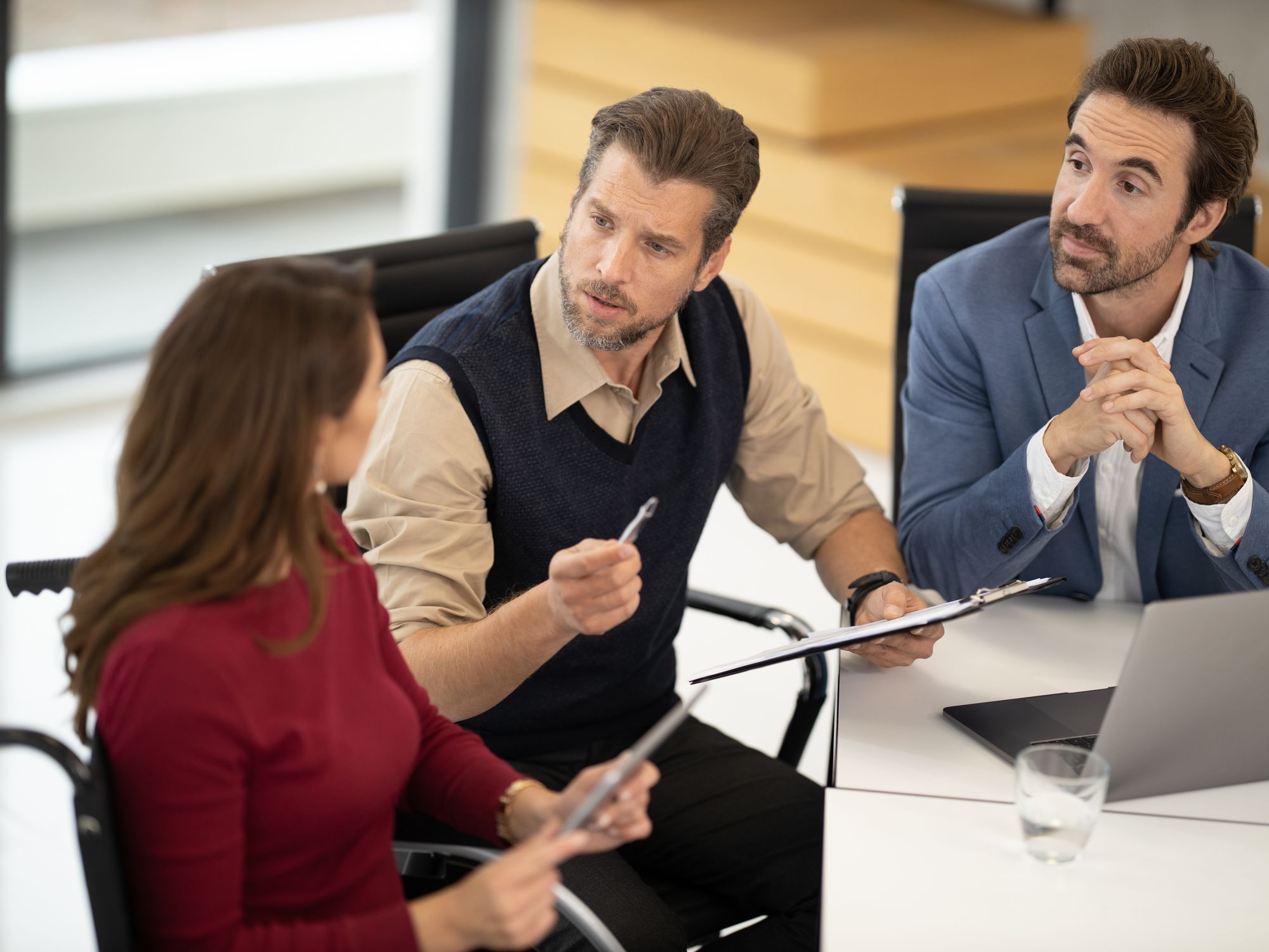 Three colleagues laughing at a meeting table