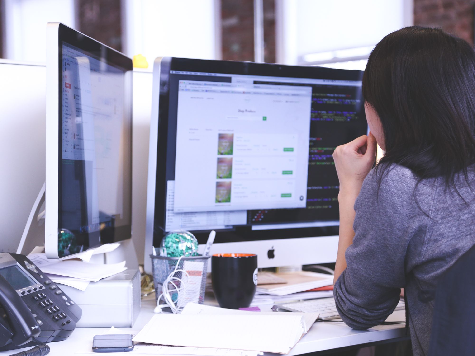 A woman working across two monitors