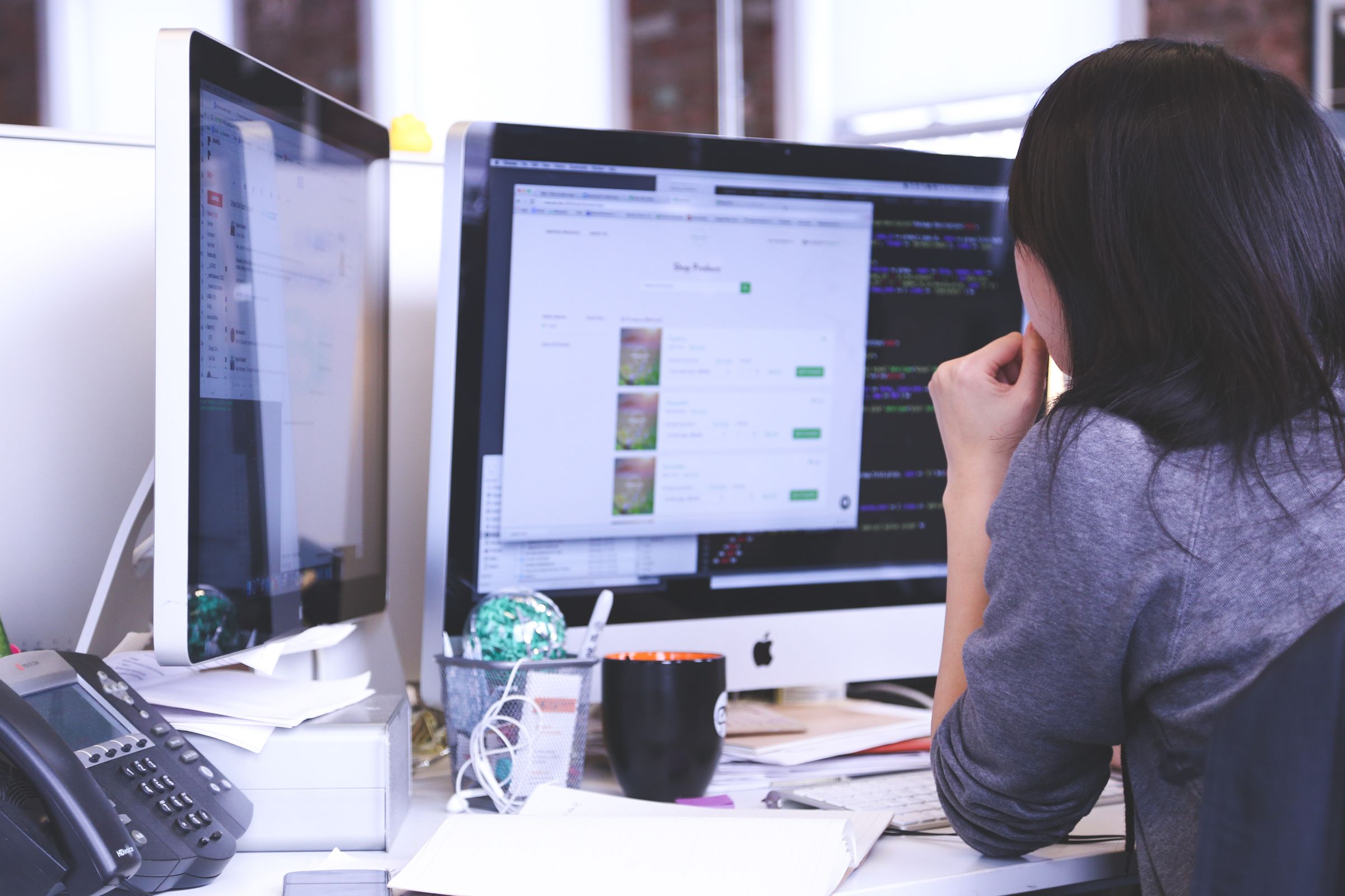 A woman working across two monitors