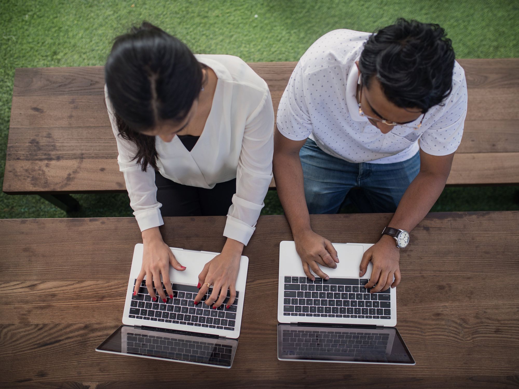 Two colleagues side by side on laptops, seen from above