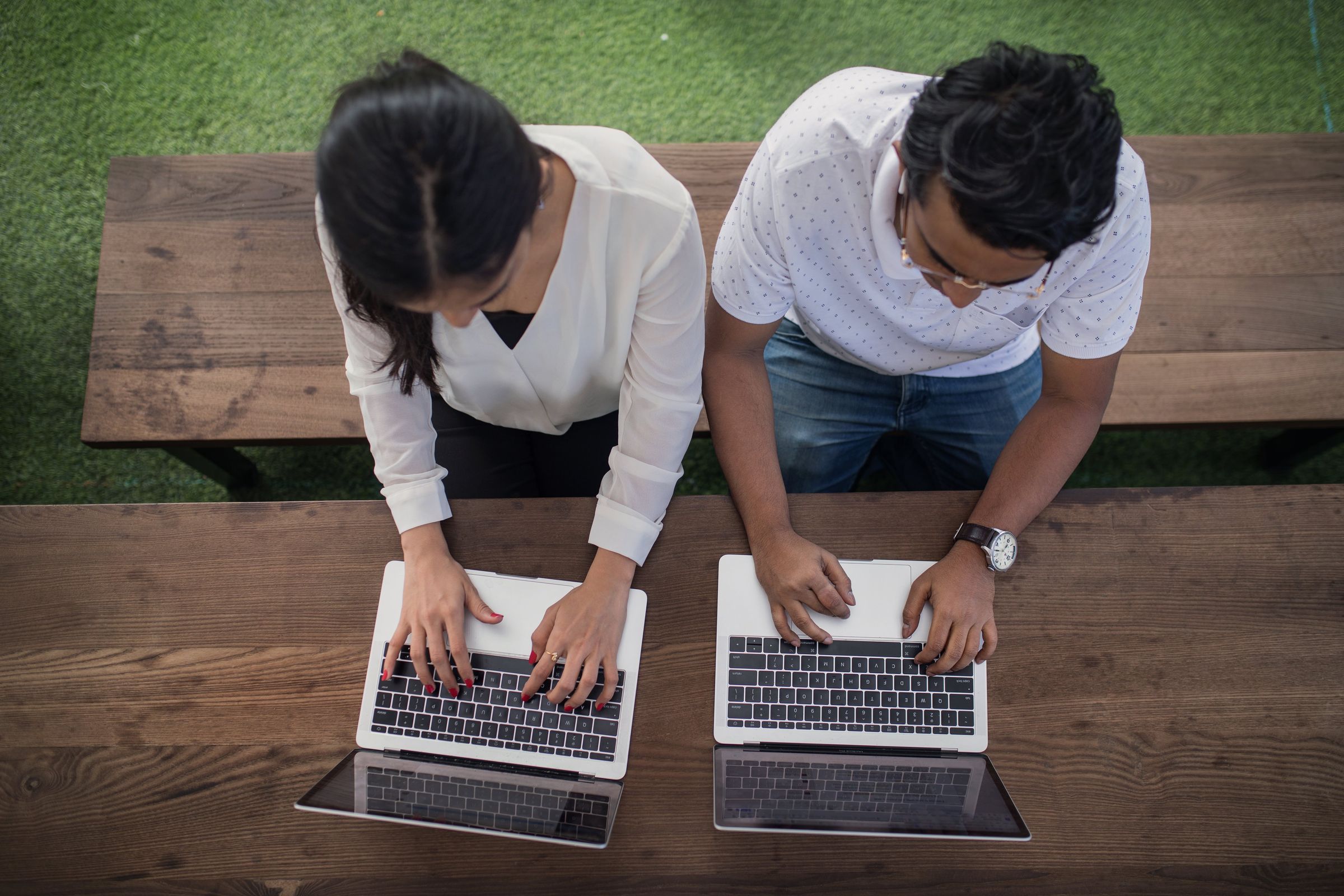 Two colleagues side by side on laptops, seen from above